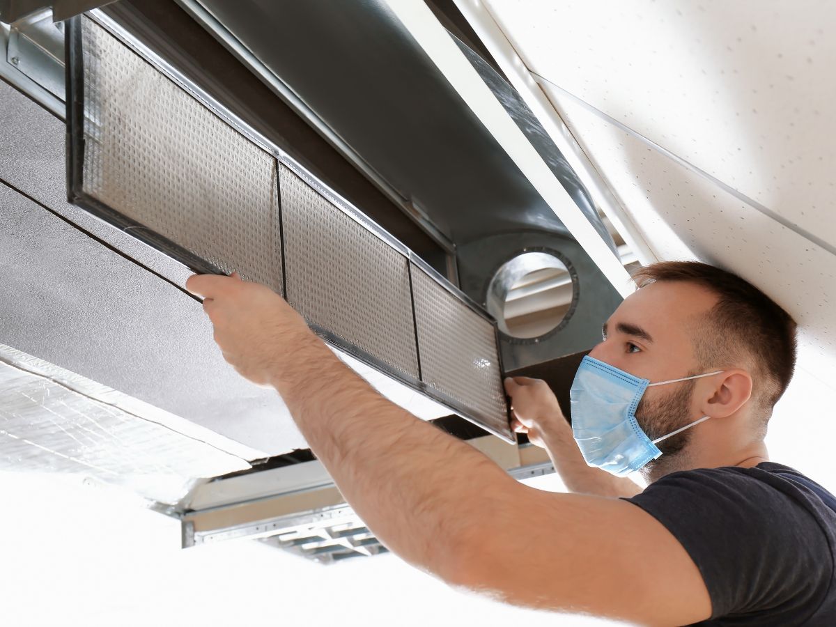 Licensed technician performing air conditioning maintenance in Northern Beaches home